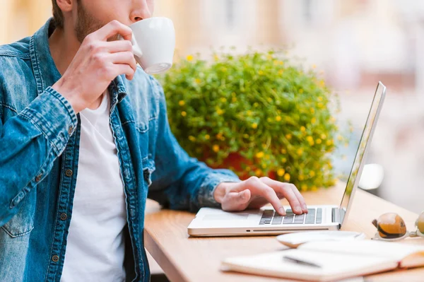 Człowiek pije kawę i pracy na laptopie — Zdjęcie stockowe