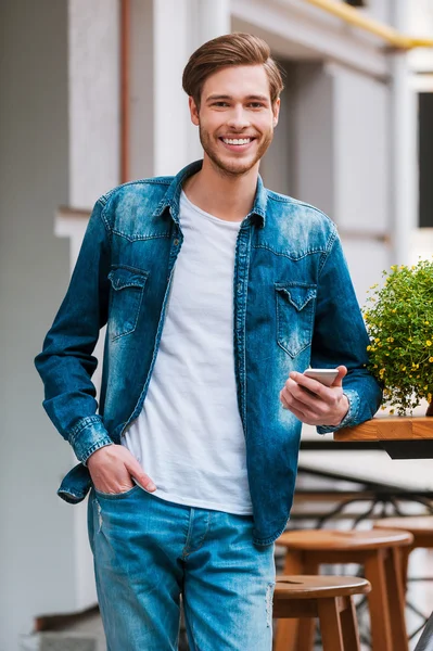 Šťastný mladý muž drží mobilní telefon — Stock fotografie