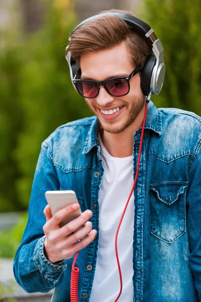 Mann mit Kopfhörer hält Handy in der Hand — Stockfoto