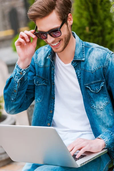 Man working on laptop and adjusting eyewear — Stock Photo, Image