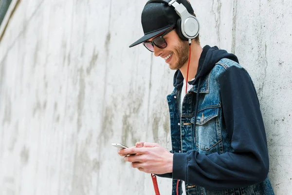 Homem em fones de ouvido segurando telefone celular — Fotografia de Stock