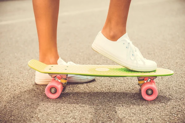 Woman holding her legs on skateboard — Stock Photo, Image