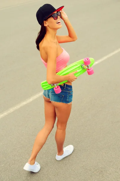 Улыбающаяся женщина держит свой красочный скейтборд — стоковое фото