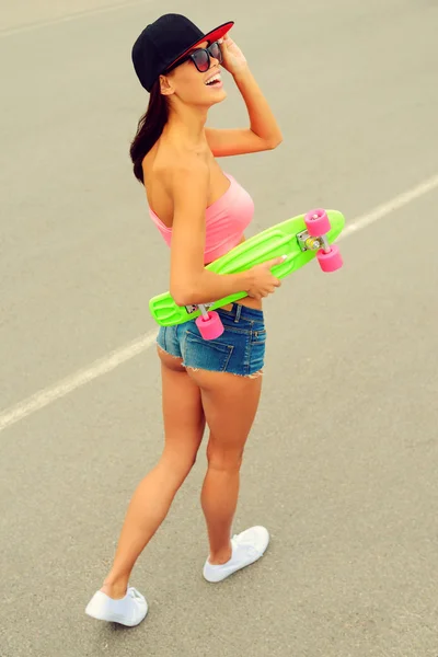 Smiling woman holding her colorful skateboard — Stock Photo, Image