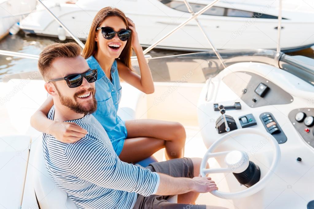 young couple driving yacht