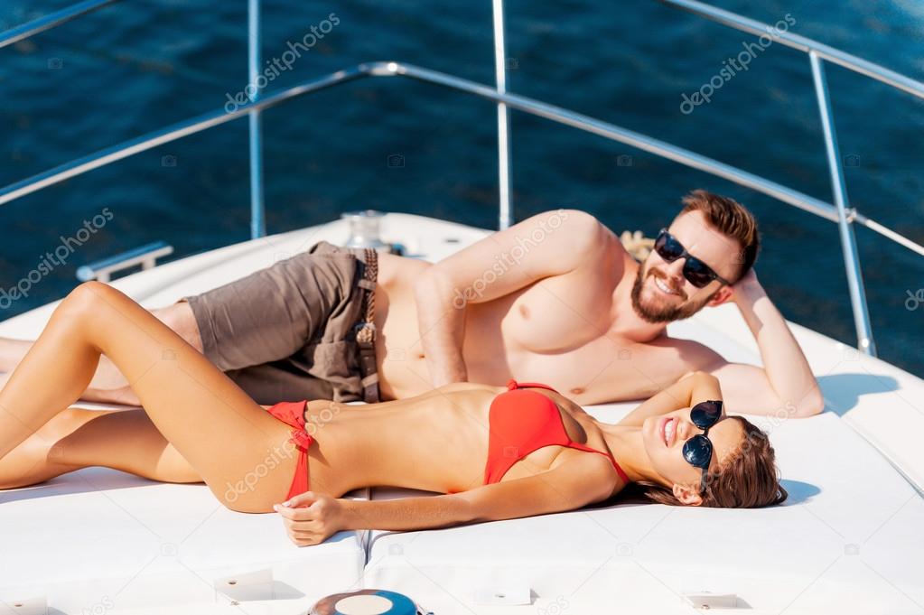 couple sunbathing on deck of yacht