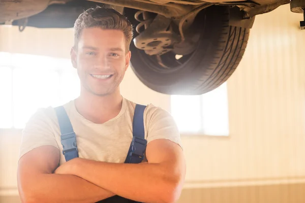 Hombre de pie debajo de un coche en el taller — Foto de Stock