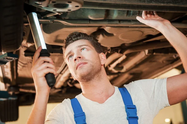 Man in uniform staande onder een auto — Stockfoto