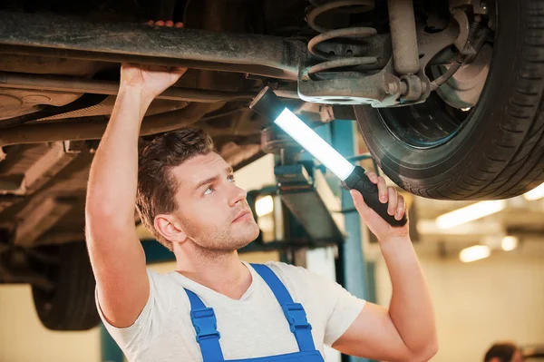 Hombre sosteniendo la lámpara mientras está de pie debajo del coche — Foto de Stock