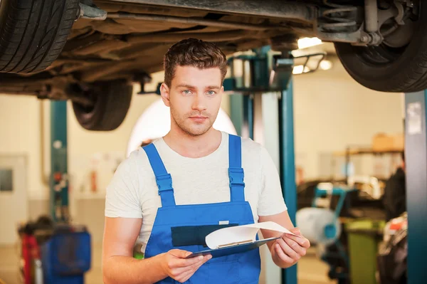 Man in uniform holding clipboard in workshop — Stock Photo, Image