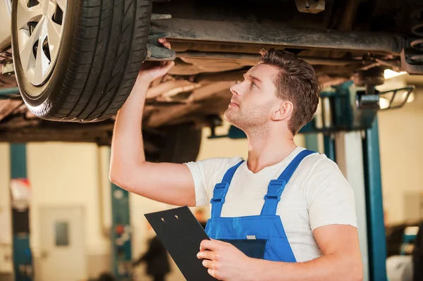 Man in uniform bedrijf lamp onder auto — Stockfoto