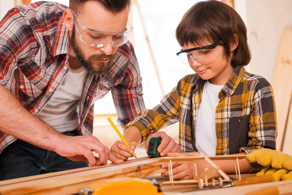 Carpenter teaching son to work with wood — Stock Photo, Image