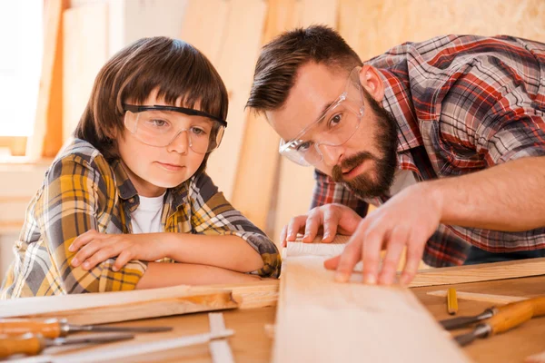 Menuisier montrant à son fils comment travailler le bois — Photo