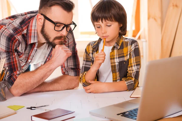 Un hombre reflexivo y su hijo trabajando juntos — Foto de Stock