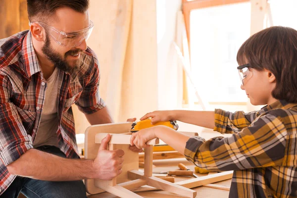 Плотник помогает сыну отполировать стул — стоковое фото