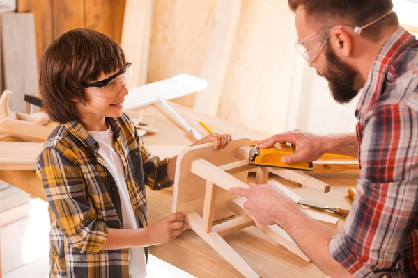 Jongen te helpen zijn vader tosand stoel — Stockfoto