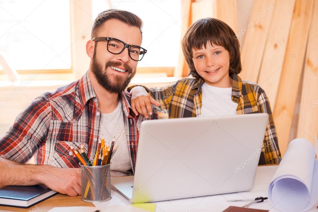man working on laptop with his son