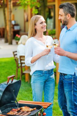 couple barbecuing meat and drinking wine