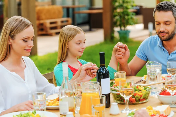 Familjen håller hand och be innan middagen — Stockfoto
