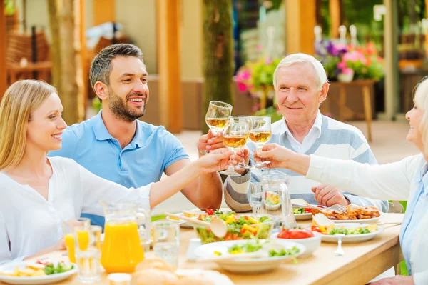 Couples jeunes et seniors assis à la table à manger — Photo