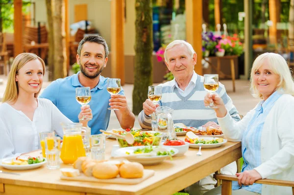 Parejas jóvenes y mayores sentadas en la mesa de comedor — Foto de Stock