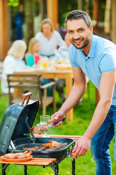 young man barbecuing meat on grill