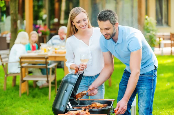 Couple barbecuing meat on the grill — Stock Photo, Image