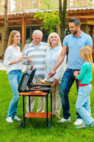 Family barbecuing meat on grill — Stock Photo, Image