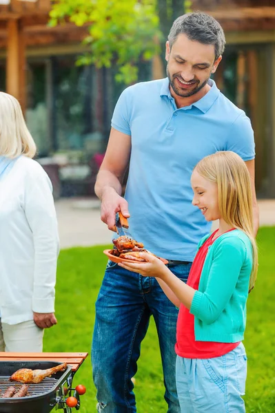 Father and daughter barbecuing meat on grill — Stock Photo, Image