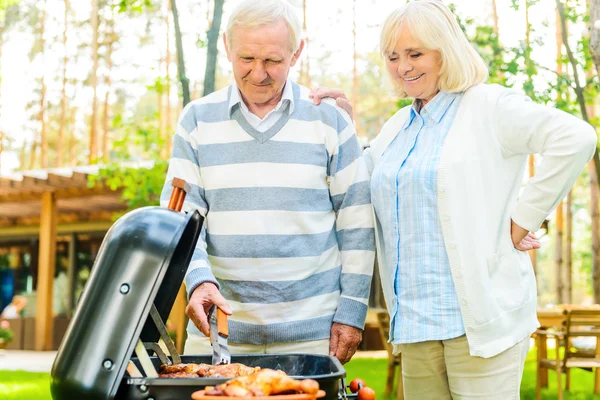 Senior paar barbecueën vlees op grill — Stockfoto