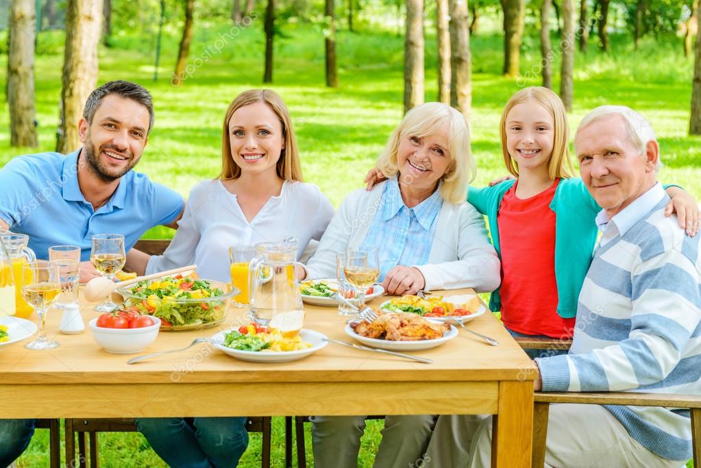 Family sitting at the dining table outdoors Stock Photo by