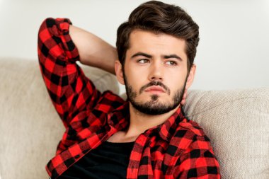 adam kanepede elini başının arkasında tutarak