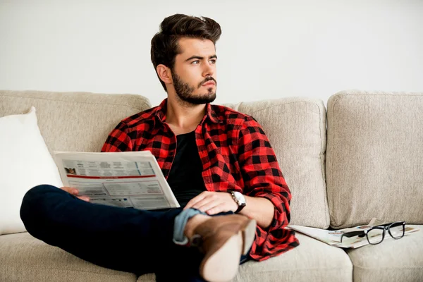 Nachdenklicher junger Mann hält Zeitung in der Hand — Stockfoto