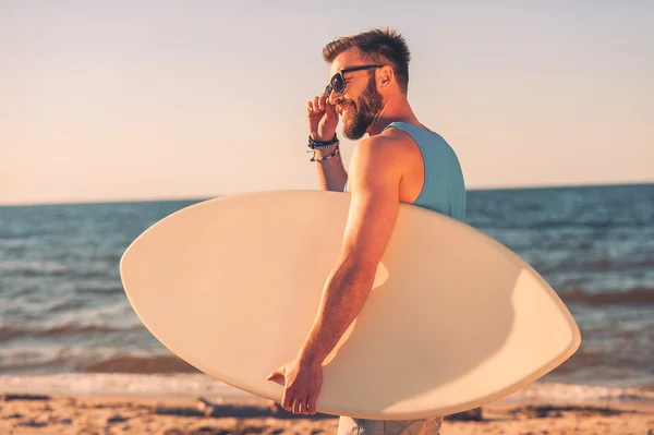 Man holding skimboard and adjusting eyewear — Stock Photo, Image