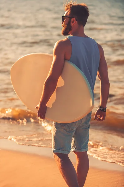 Man holding skimboard walking along beach — Stock Photo, Image