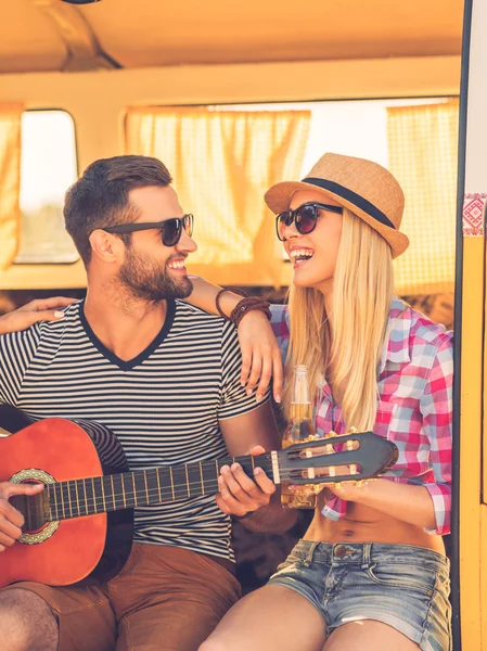 Namorada com o homem sentado em minivan e tocando guitarra — Fotografia de Stock