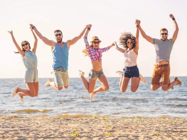 Щасливі молоді люди стрибають на пляжі — стокове фото