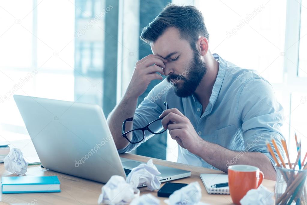 Frustrated young beard man massaging nose