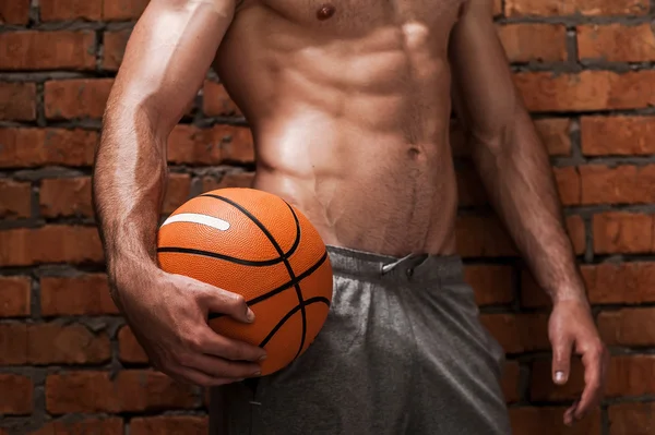 Muskularny mężczyzna trzyma piłkę do koszykówki — Zdjęcie stockowe