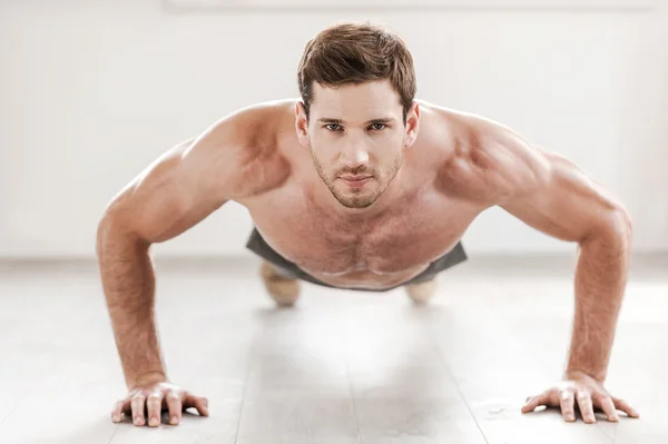 Confident muscular man doing push-ups