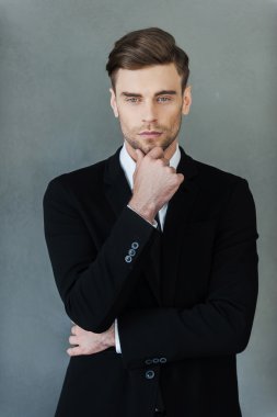 Confident businessman holding hand on chin