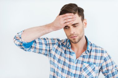Frustrated young man in shirt touching forehead