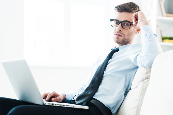 Uomo d'affari che lavora sul computer portatile mentre è seduto sul divano — Foto Stock