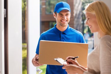 delivery man holding and woman putting signature