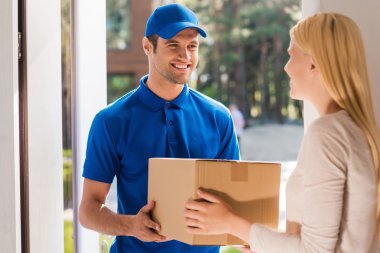 delivery man giving cardboard box to woman