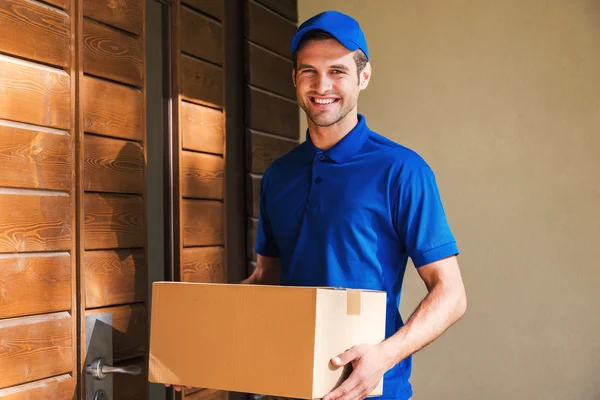 Joven mensajero sosteniendo caja de cartón — Foto de Stock