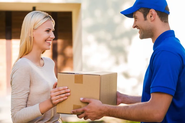 Delivery man giving a cardboard box to woman — Stok fotoğraf