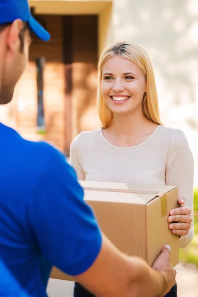 Delivery man giving cardboard box to woman — Stockfoto