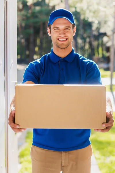 Delivery man stretching out cardboard box — Stok fotoğraf
