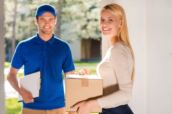 Woman holding cardboard box with delivery man — Stok fotoğraf